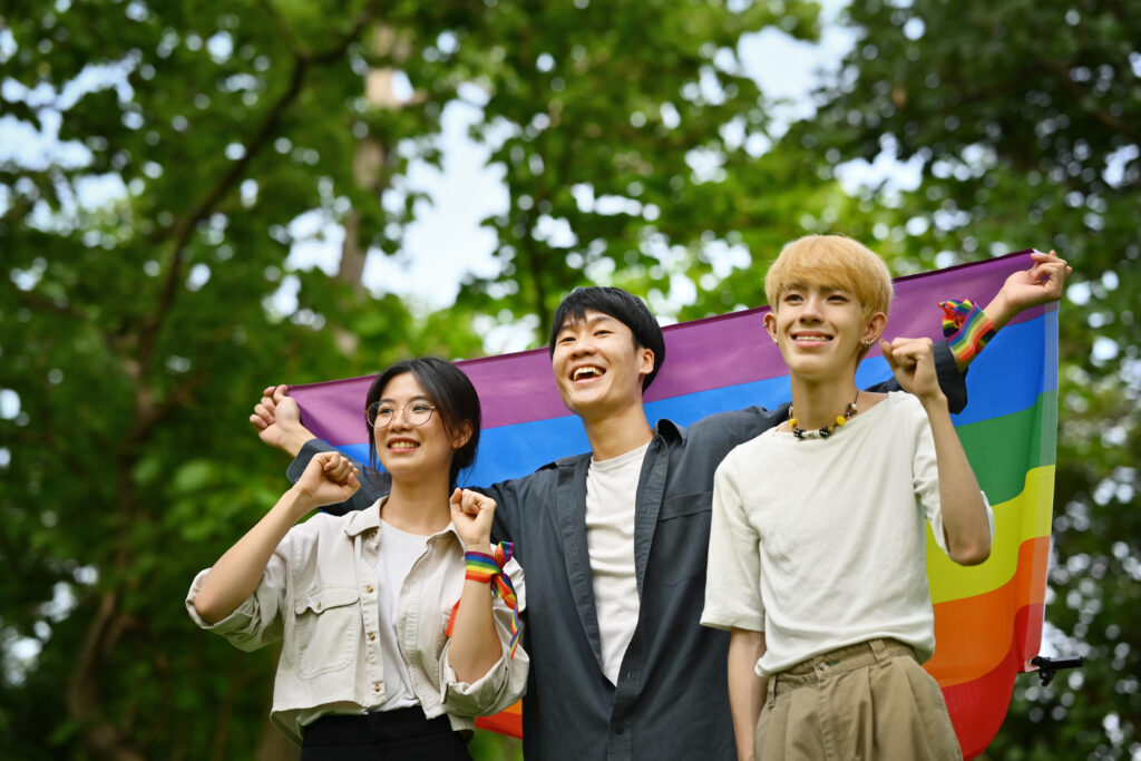 Group of young people holding pride rainbow flag, supporting LGB