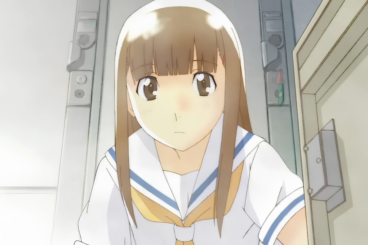 Shuichi Nitori, with long brunette hair and wearing a sailor-style school uniform, looks towards the viewer