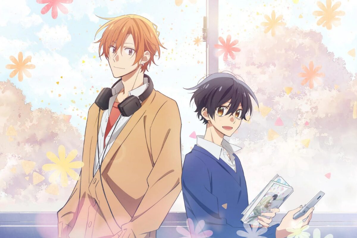 Sasaki Shuumei, left, faces left at a 45 degree angle to the viewer, smiling with his hands in his pocket and headphone around his neck. Miyano Yoshikazu stands with his back to Sasaki, smiling and holding BL manga