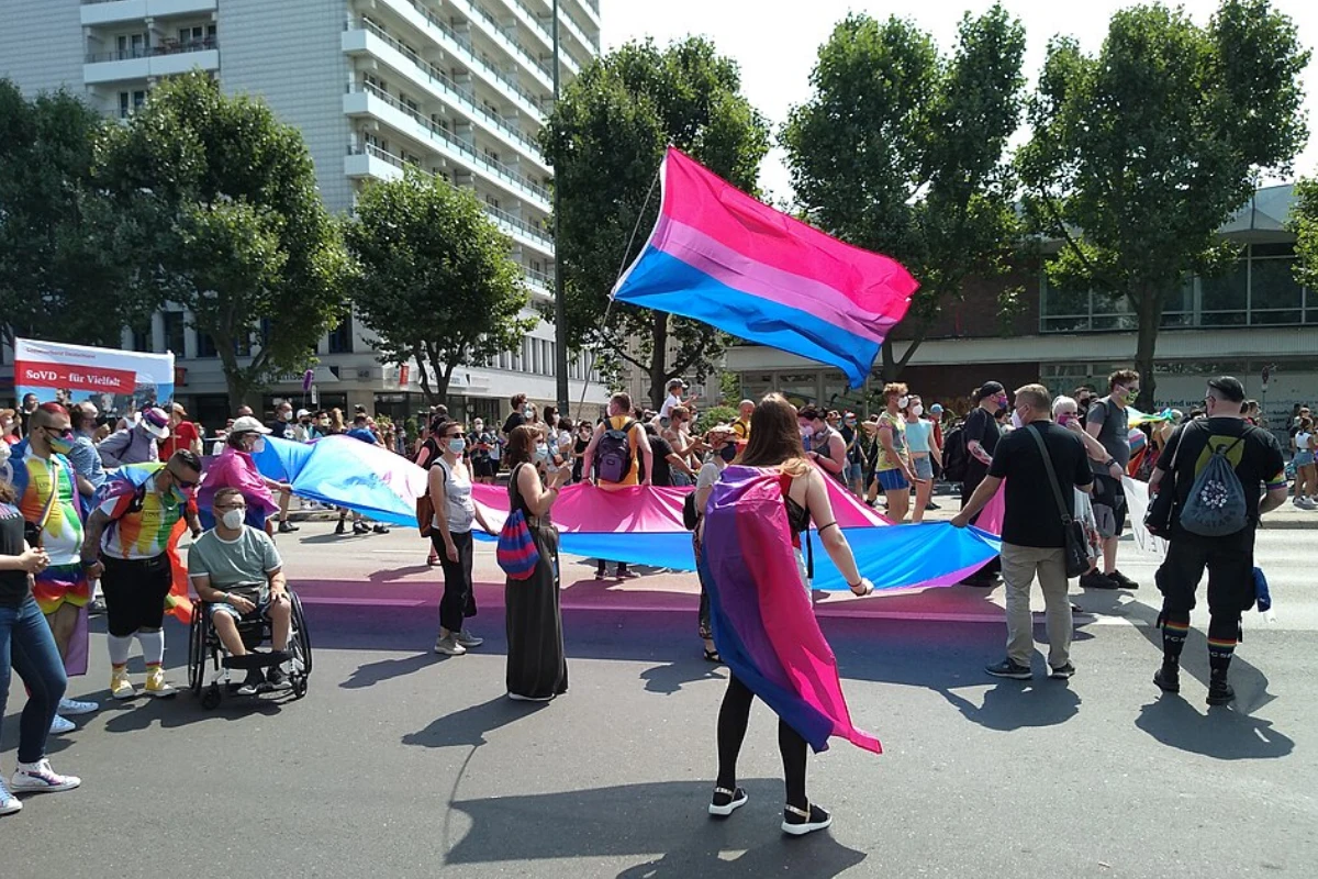 What Is It Like to Be Bisexual in Japan? 15 Pride marchers carry and wear large bisexual pride flags in pink, purple, and blue during a street parade.