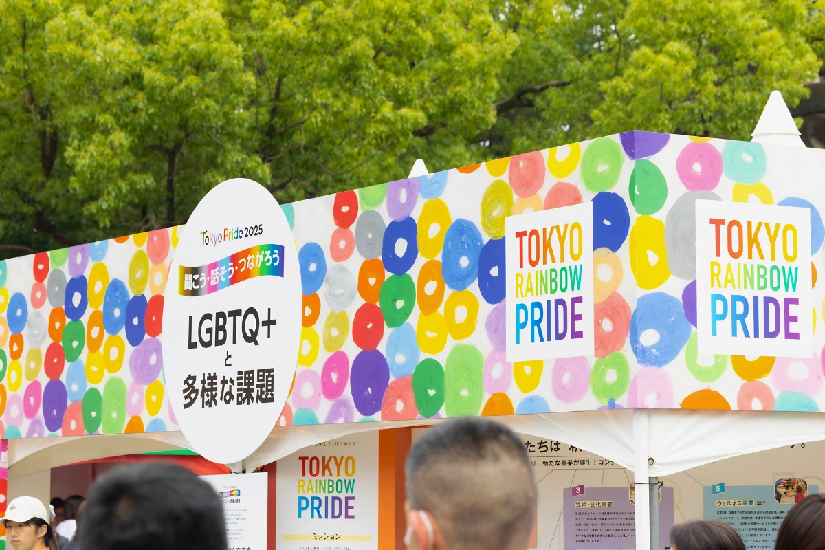 A colourful booth at Tokyo Rainbow Pride with people walking past