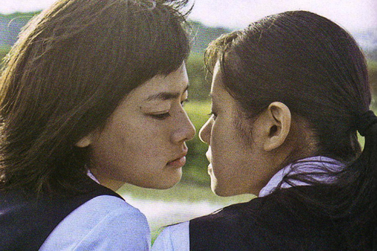10 Best Japanese Lesbian Movies & Series to Watch 15 Two schoolgirls in uniform facing each other closely in bright sunlight.