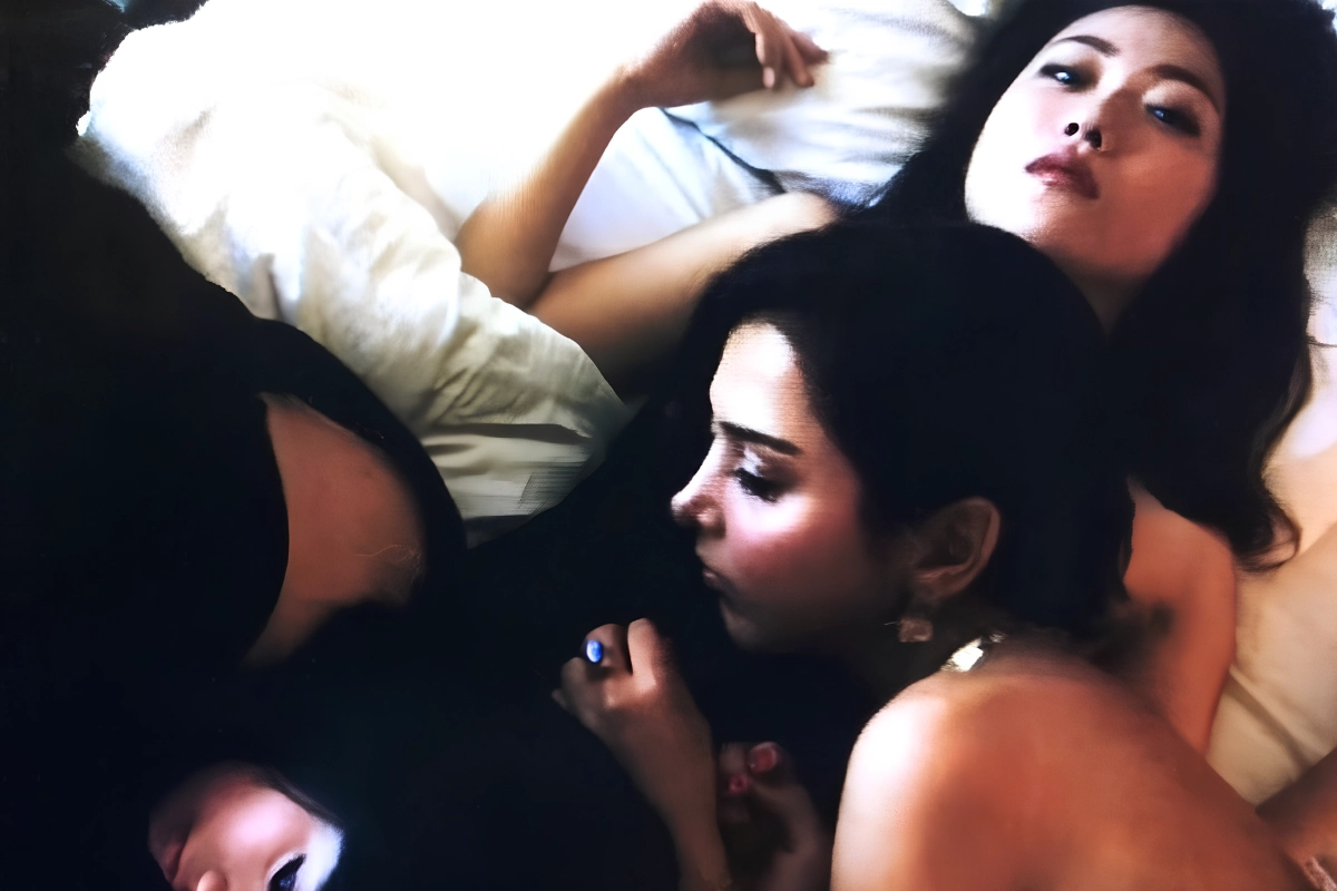 10 Best Japanese Lesbian Movies & Series to Watch 16 Two women reclining closely together on a bed, with one looking up at the camera.