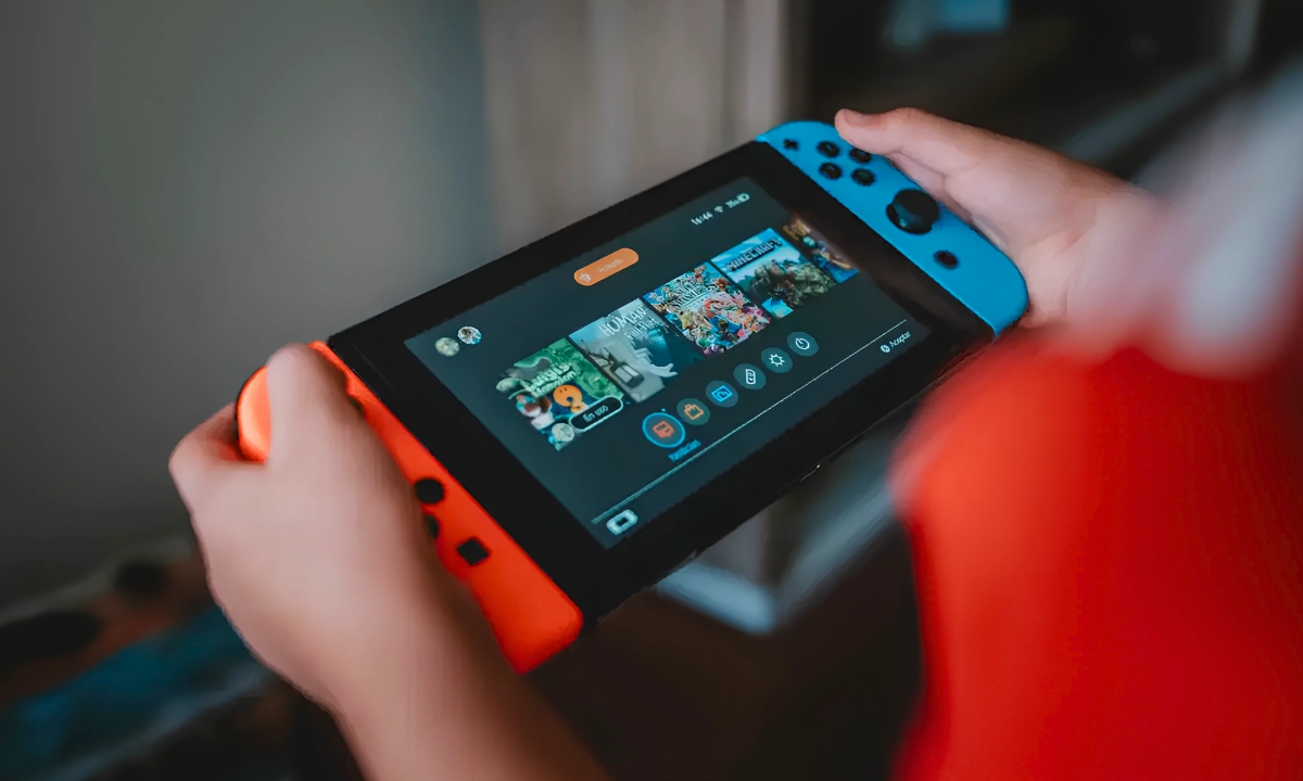 Person holding a Nintendo Switch with the game selection menu visible on screen.