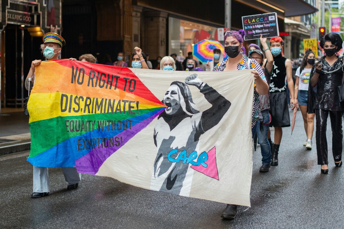 Marchers move down a street in Sydney. At the front, two hold a banner reading “No right to discriminate! Equality without exceptions!”
