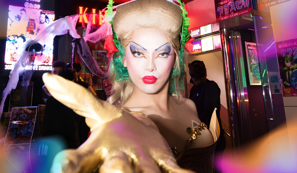 Drag queen stood outside of Kingdom gay club, staring into the camera with their hand reaching out towards the camera.