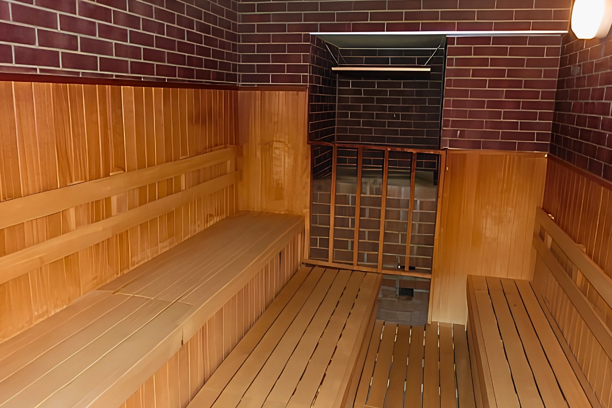 Wood-paneled sauna at 24 Kaikan Shinjuku with tiered benches and dark brick walls.