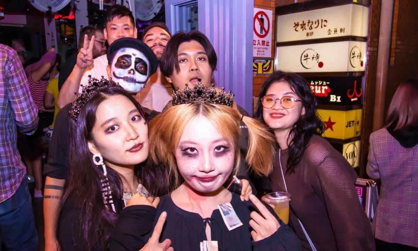 Group of costumed partygoers pose together outside nightlife venues during a Halloween event in Japan.