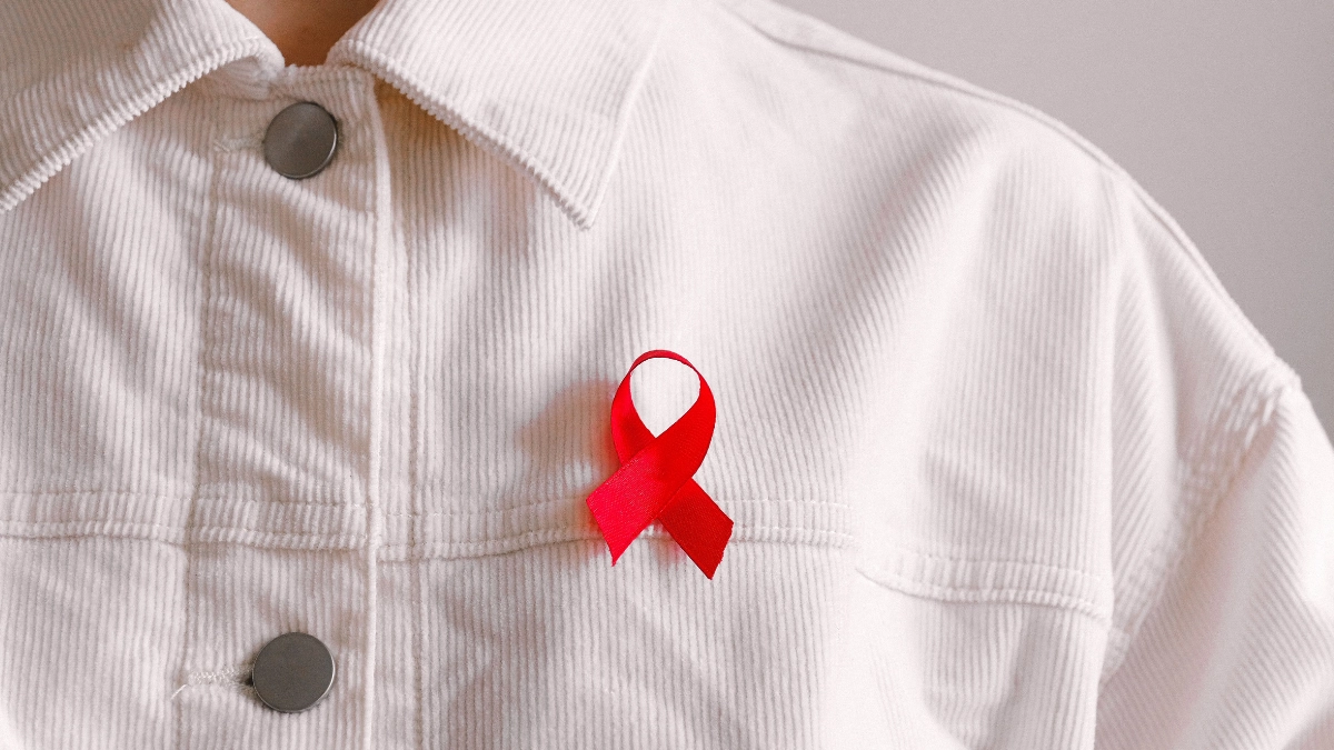 Hooking Up in Japan: A Guide for Gay and Bisexual Men 16 Red HIV awareness ribbon pinned to a white shirt, highlighting sexual health, STI testing, and safer sex in Japan.
