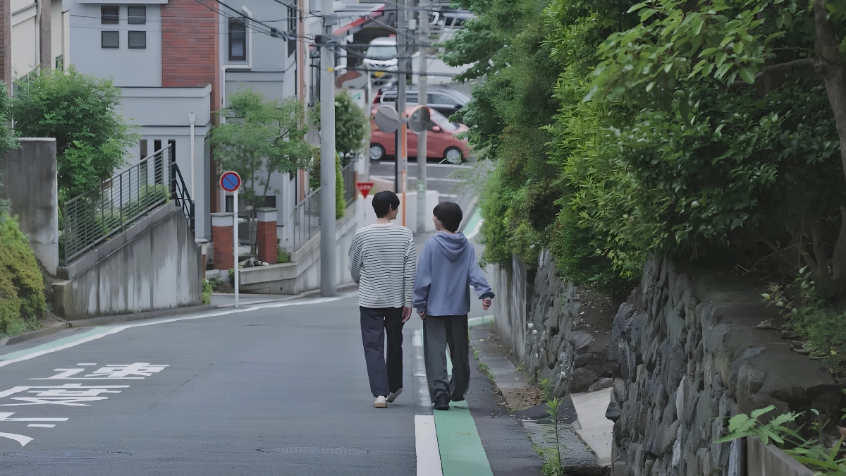 Rent a Boyfriend in Japan: How It Works, Costs, Rules, and Gay Options 12 Two men walking closely down a hill in a rural area, surrounded by trees and greenery.