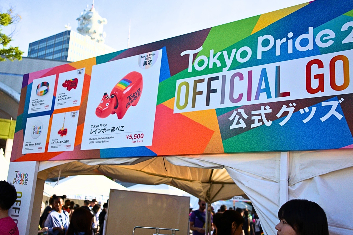 Tokyo Pride 2026 official merchandise booth with a large rainbow-colored sign displaying Pride-themed goods, including a rainbow Akabeko figurine.