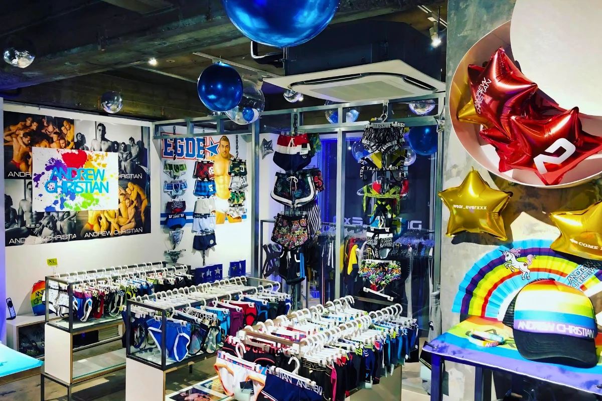 Interior of a colorful men’s underwear and swimwear shop, with racks of brightly patterned briefs, trunks and accessories beneath blue and metallic balloons.