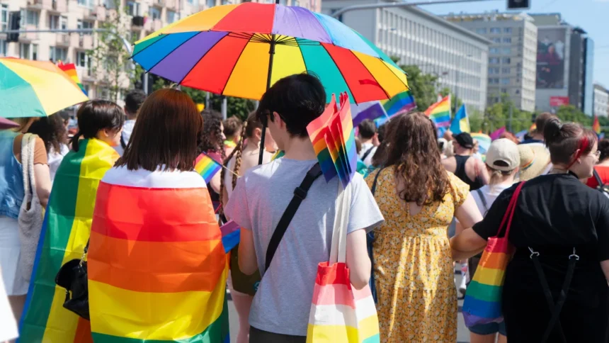 Participants celebrating at a Pride parade festival with rainbow flags and umbrellas, representing the global LGBTQ+ community.