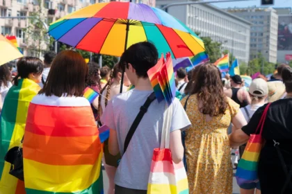Participants celebrating at a Pride parade festival with rainbow flags and umbrellas, representing the global LGBTQ+ community.