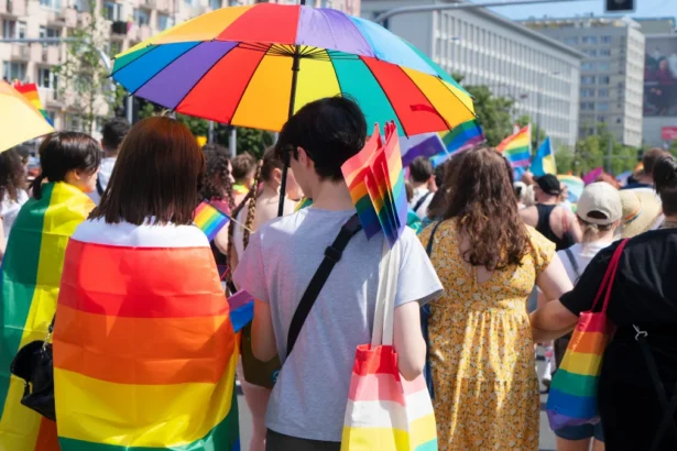 Participants celebrating at a Pride parade festival with rainbow flags and umbrellas, representing the global LGBTQ+ community.