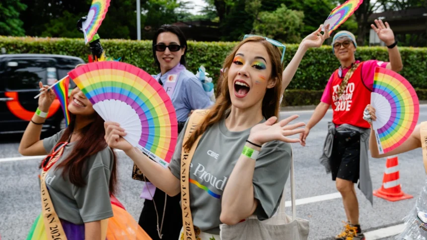 People celebrating at Tokyo Pride with rainbow fans, Pride flags and colourful makeup, supporting an lgbtq friendly Japan.
