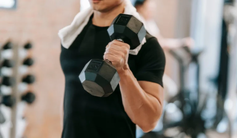 Trans person lifting a dumbbell inside a fitness facility in Japan.