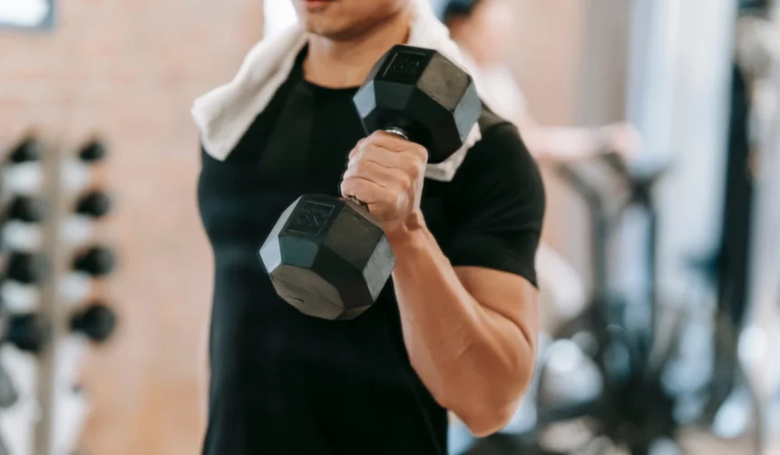 Trans person lifting a dumbbell inside a fitness facility in Japan.
