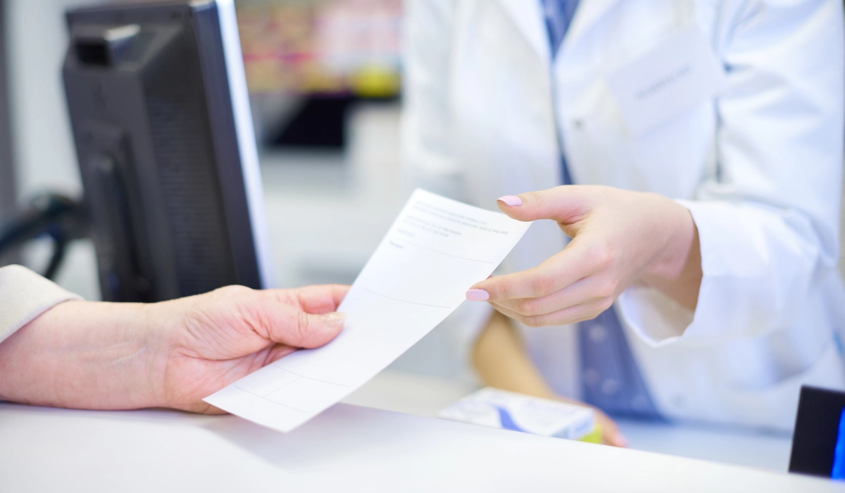 Handing a medical prescription to a pharmacist at a clinic counter to fill an HRT prescription in Japan.