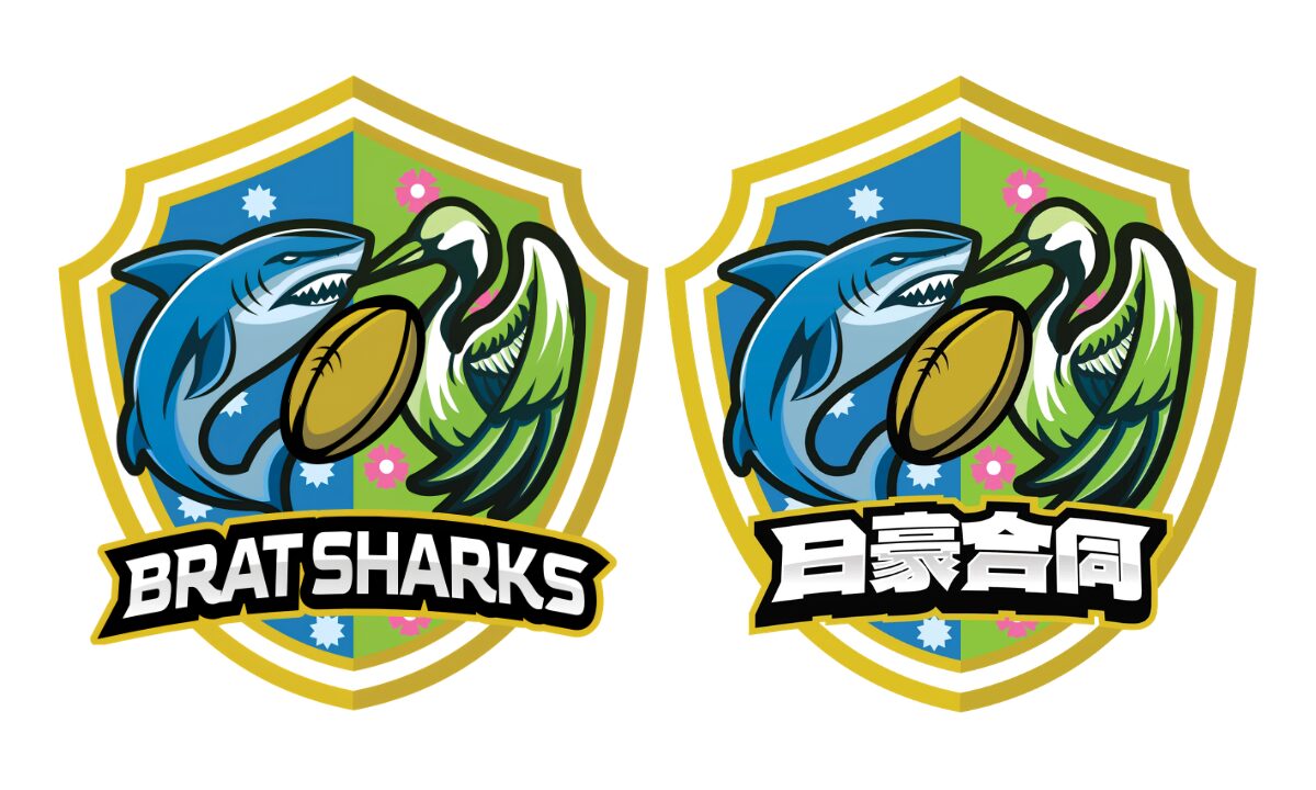 Illustrated shield with a cartoon shark on the left, with a crane on the right, a rugby ball between them. The shield is displayed twice, with “BratSharks” superimposed on the left, and the Japanese equivalent on the right