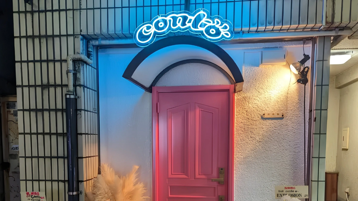 Image of pink entrance door to bar CONTO along with neon light of CONTO highlighting above the door.