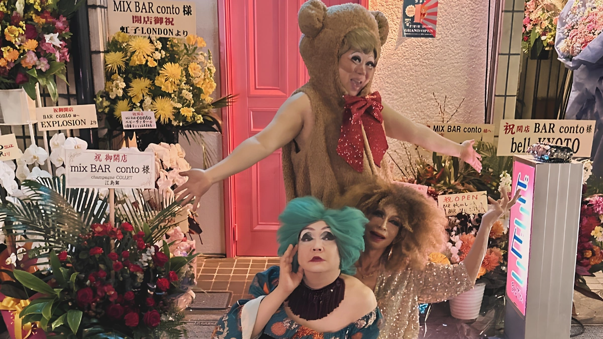 Image of three drag queens outside of bar CONTO all dressed up in various costumes and posing in front of the entrance door to the bar.