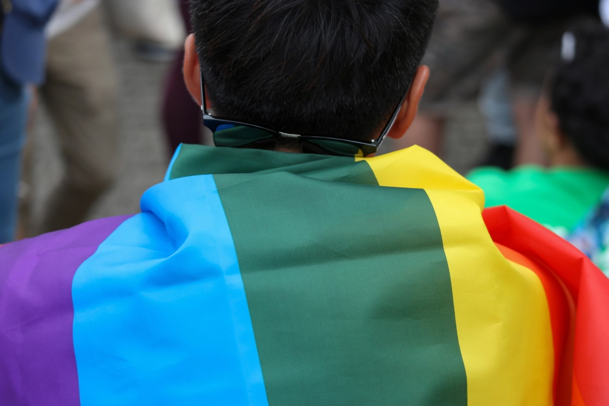Toyama to Hold Its First Pride March on 21 September 2026 13 Person wearing sunglasses holds a rainbow pride flag across their back.
