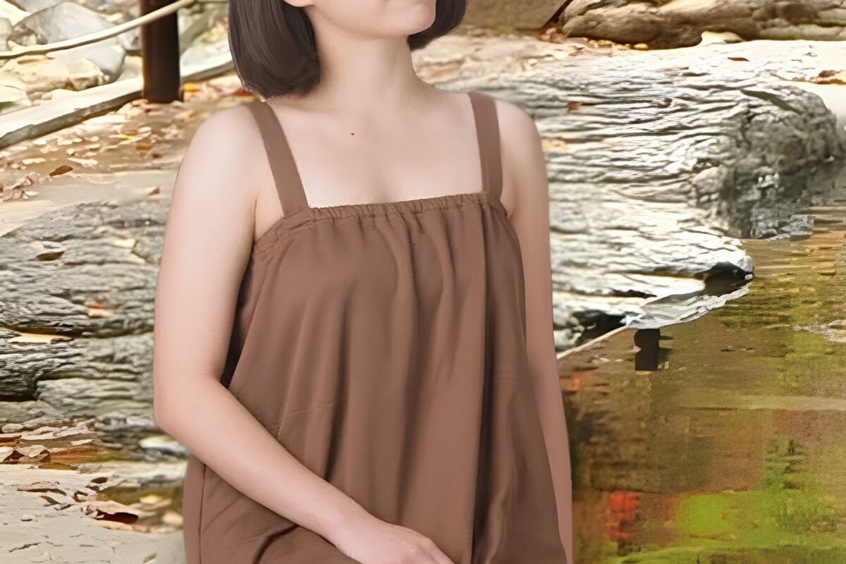 A woman models one of the Takaragawa Onsen bathing garments. It is a brown, dress-like garment that covers her body from her breasts to her knees