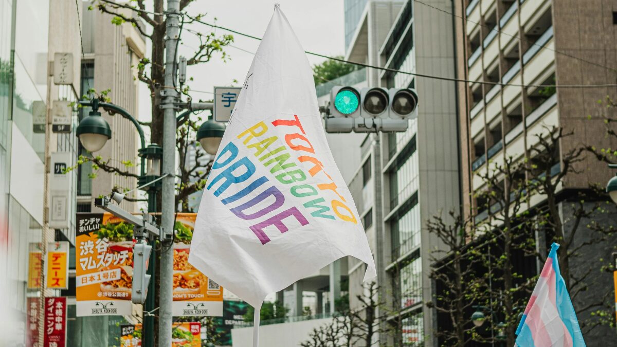 The History of Tokyo Pride: Protest, Party and Progress 15 A flag reading “Tokyo Rainbow Pride” is raised high against the backdrop of a Tokyo street