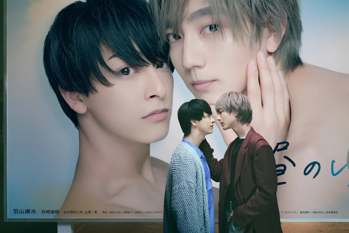 Two young Japanese men stand close together in front of a large romantic poster showing their faces, leaning toward each other as if about to kiss.
