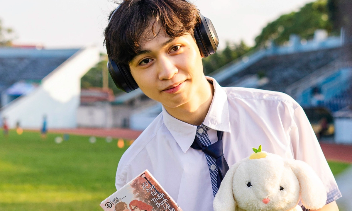 Guy in smart casual clothing is holding a rabbit plushie and manga, while wearing headphones