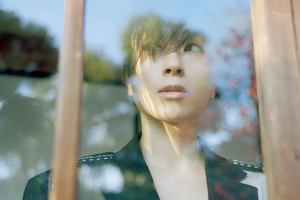 LGBTQ+ Japanese Celebrities to Know, From Pioneers to Today 30 Hikaru Utada stands in front of a window and looks outside as the trees are reflected back against the window glass. They are wearing a black and white suit jacket