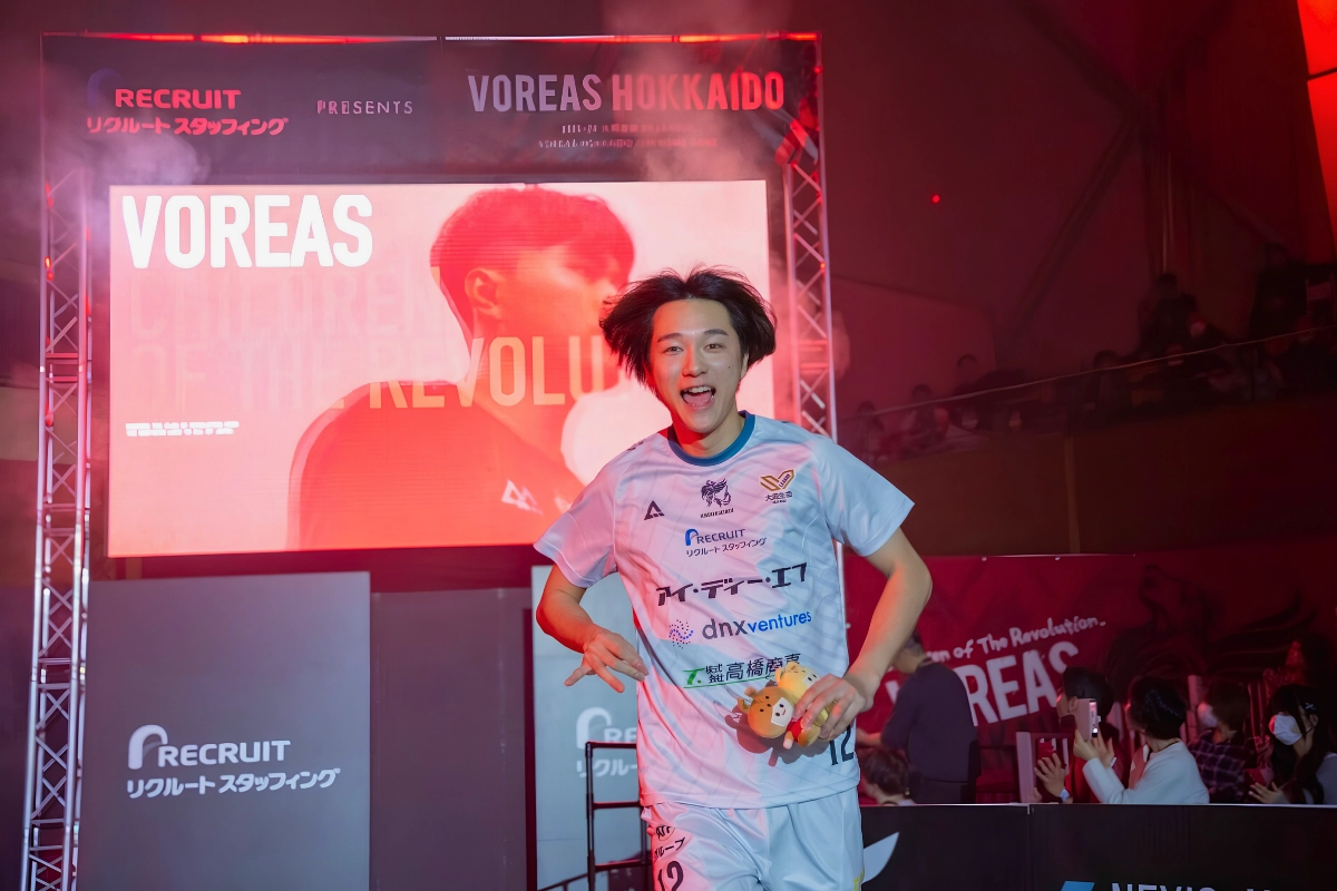 Rui Takahashi Comes Out as Gay, Inspires Reon Arao 10 Male volleyball player in a Voreas Hokkaido uniform poses in front of a brightly lit team display