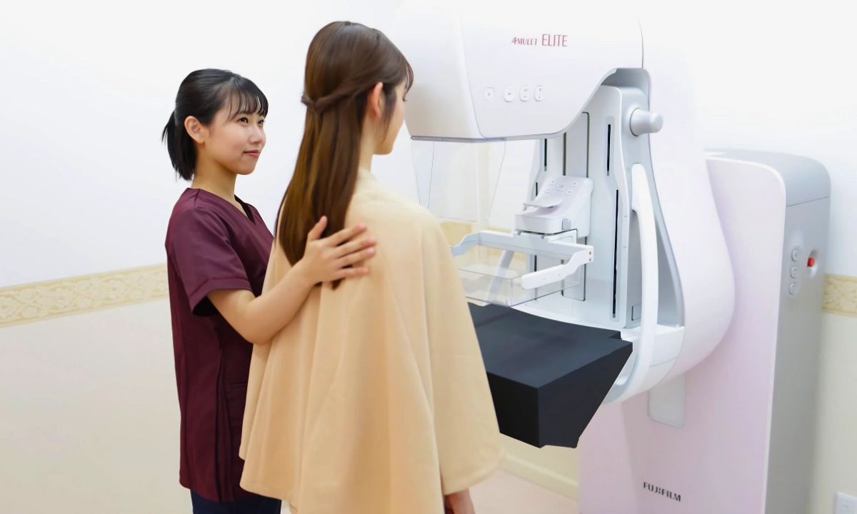 A radiologic technologist positions a patient at a mammography machine for a breast screening.