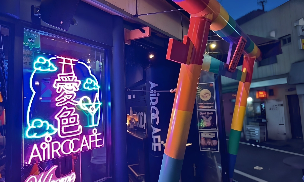 Rainbow-colored entrance and neon sign at AiiRO CAFE in Shinjuku Ni-chome at night.