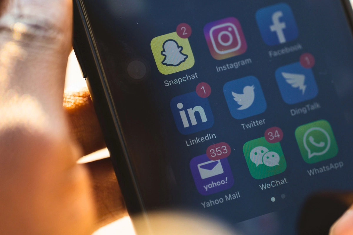 Close-up of a smartphone screen displaying social media and messaging app icons, including Instagram, Facebook, Twitter, Snapchat, LinkedIn, WeChat, and WhatsApp.